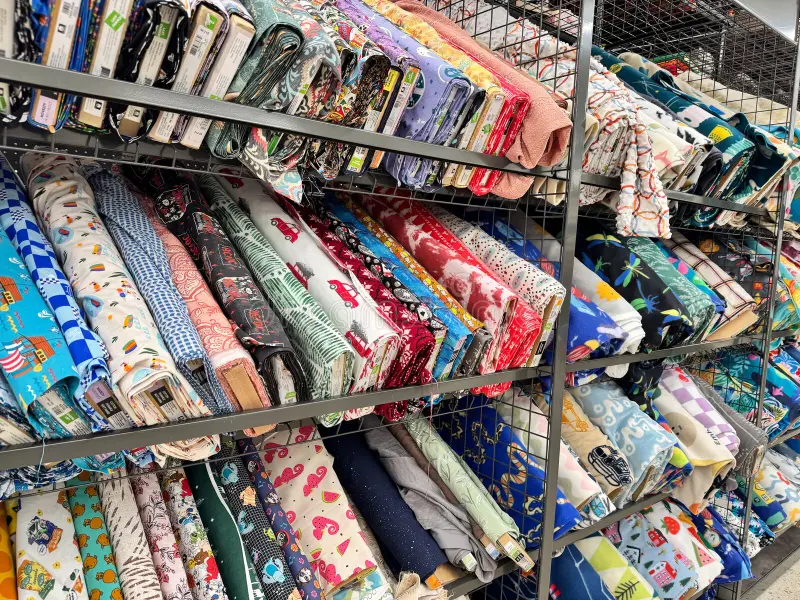 Stack of colorful JOANN quilting fabric bolts folded in a maker studio